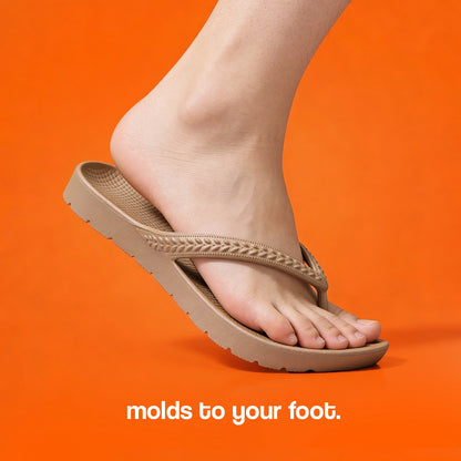 Khaki Brown Arch Support Flip Flops molding to a foot on an orange background.