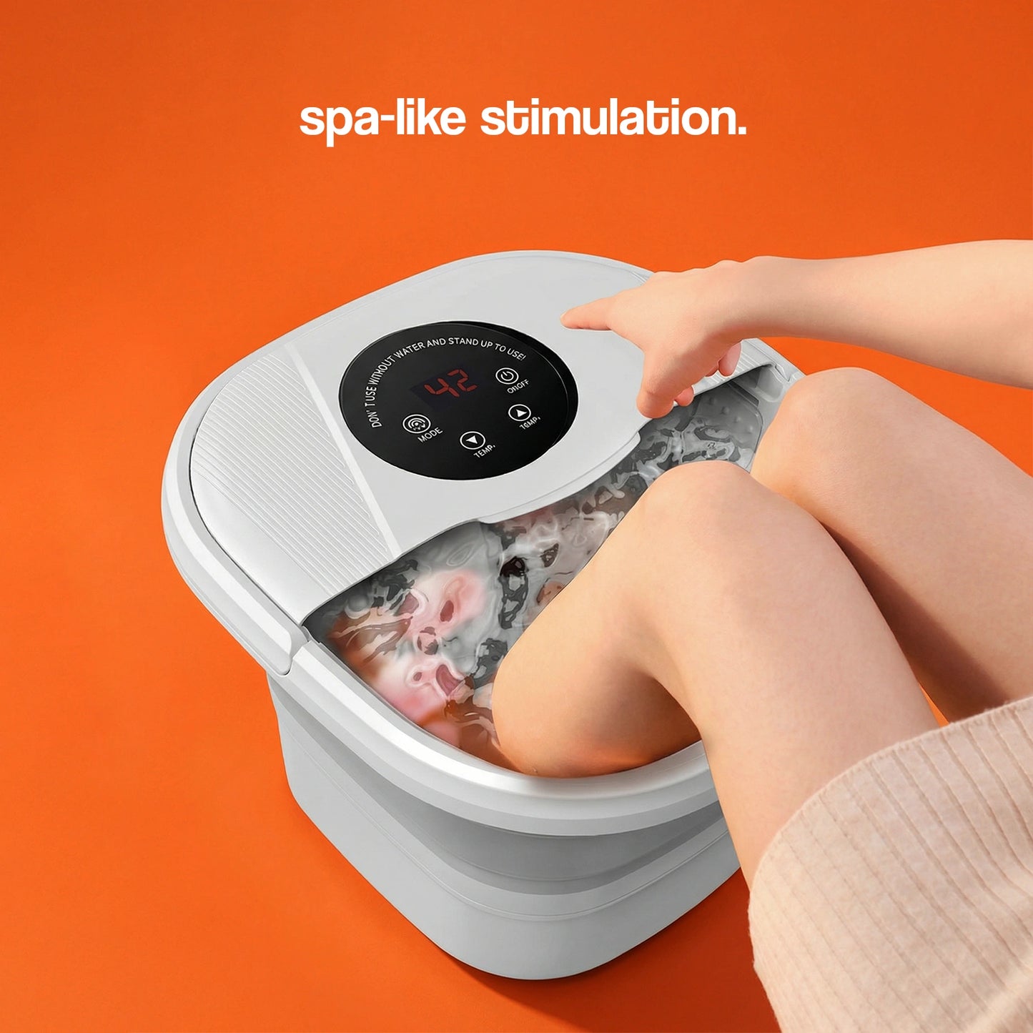 Foot spa with a digital control panel, water bubbling, and a person's feet submerged, set against an orange background.
